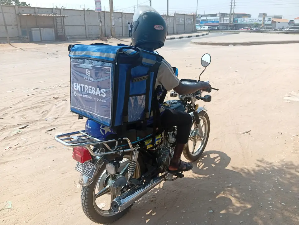 Estafeta da BEN & BER Delivery em motociclo com mala de entregas, em Luanda