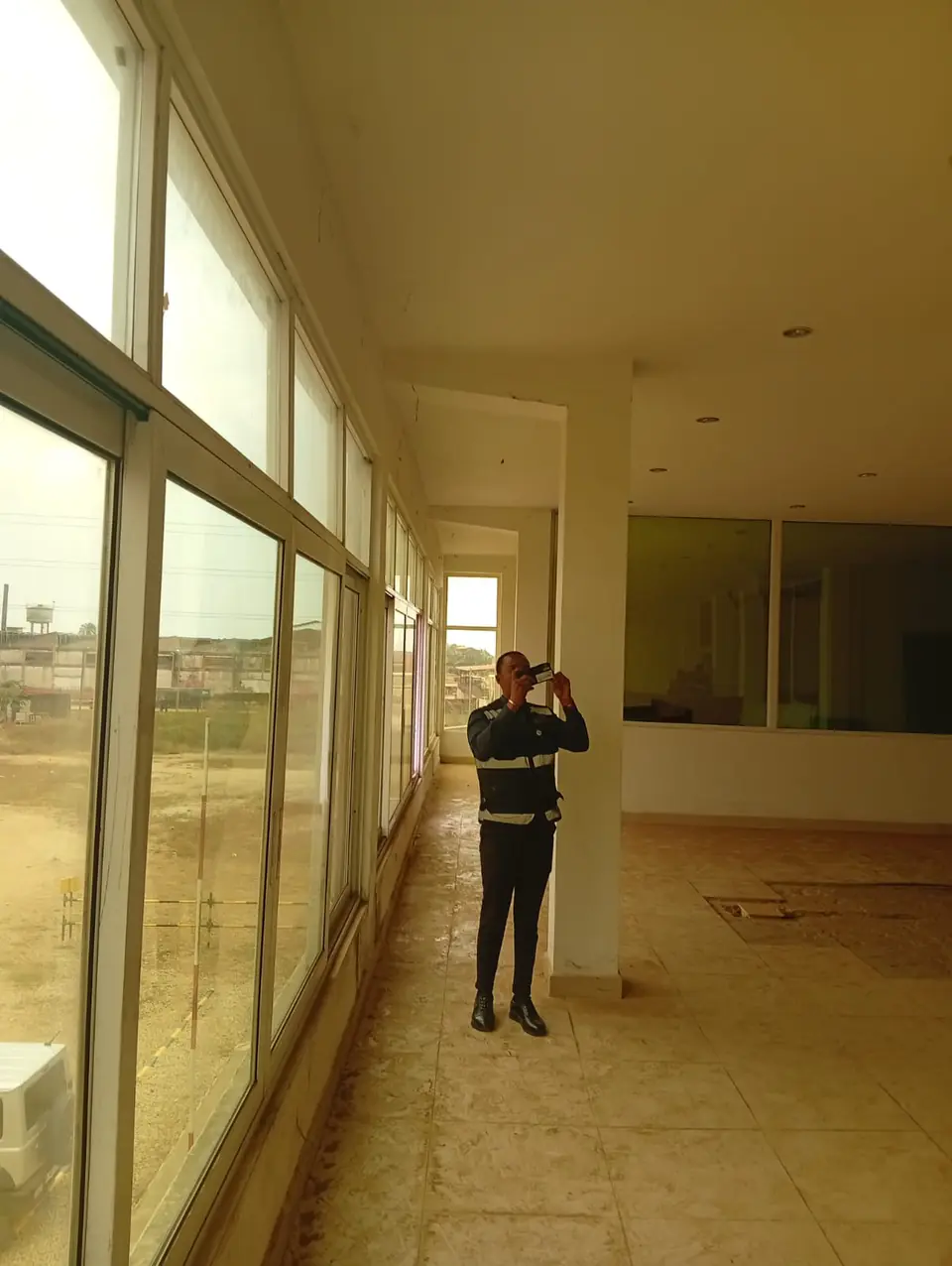 Técnico a fazer medições junto às janelas de um piso de escritórios