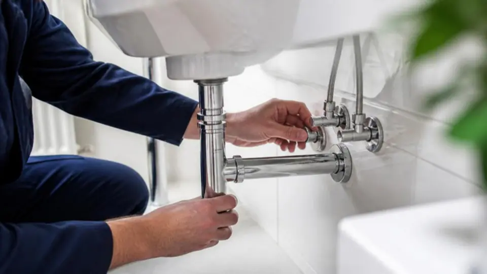 Canalizador a instalar tubagem e válvulas cromadas por baixo de um lavatório